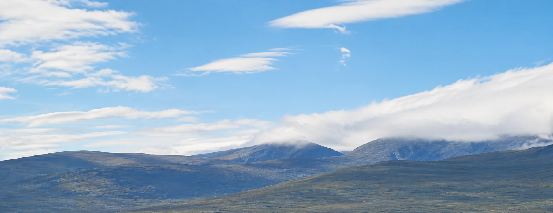 Fjällandskap i Härjedalen med vidsträckta vidder, blå himmel och moln över fjälltopparna